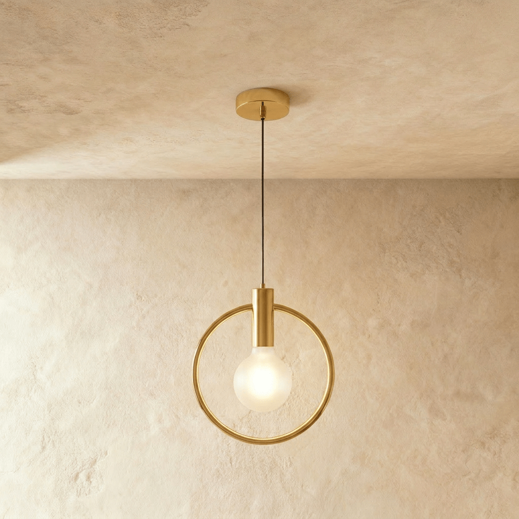 Clérachic gold ring pendant with a bare frosted bulb on a brass holder, hung from a round gold canopy in a studio
