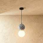 Clérachic two-globe pendant light with a grey terrazzo sphere above a glowing opal glass globe on a slim black cord.
