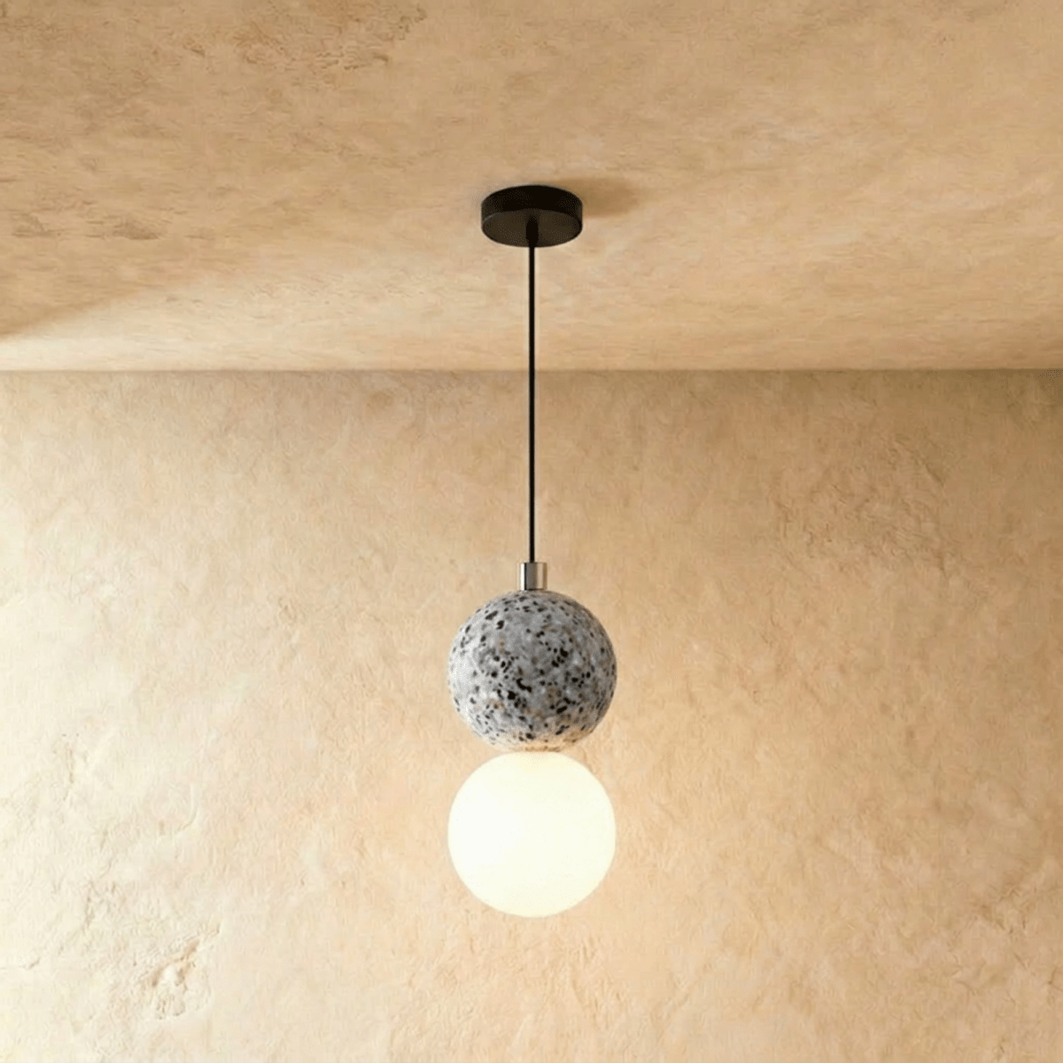 Clérachic two-globe pendant light with a grey terrazzo sphere above a glowing opal glass globe on a slim black cord.