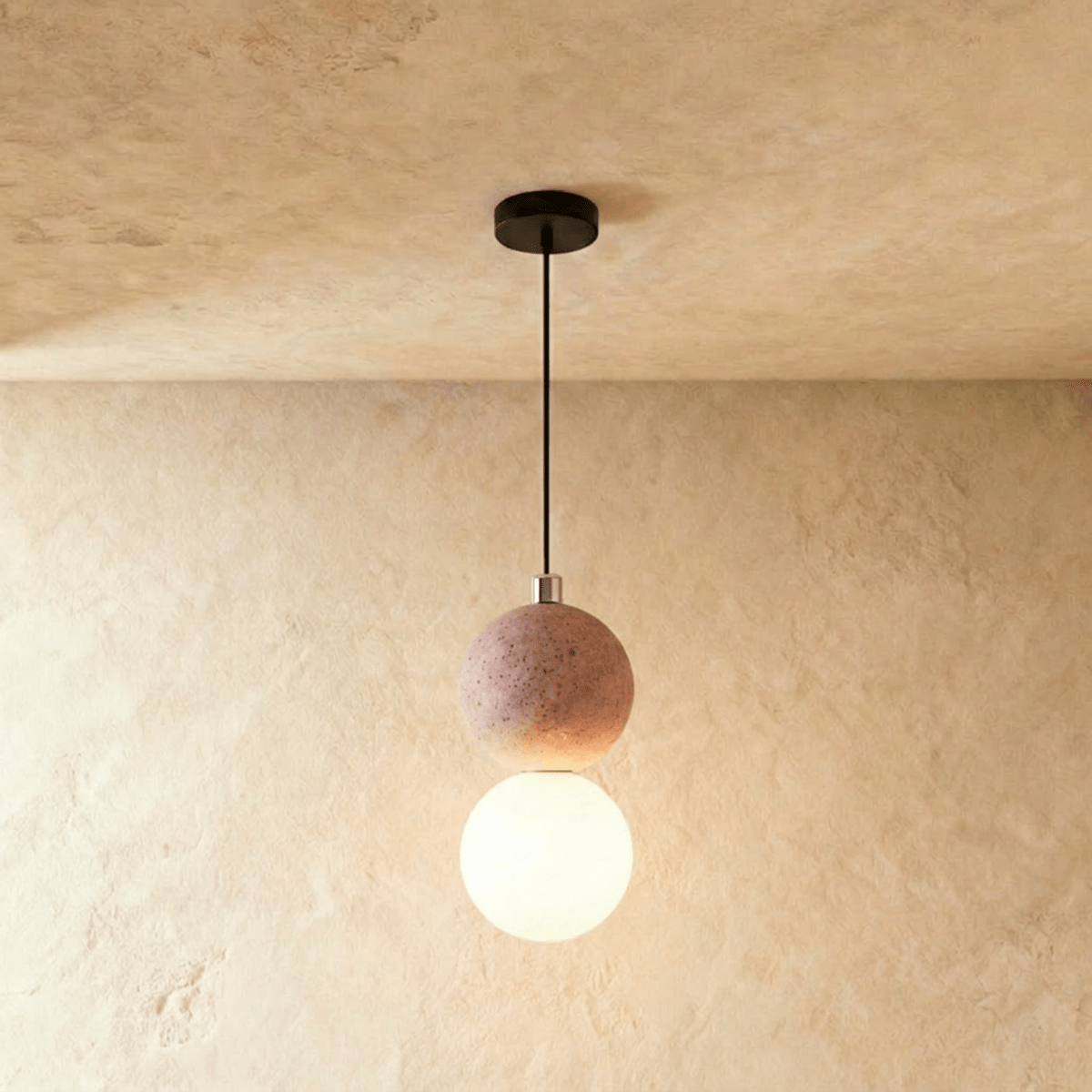 Clérachic two-globe pendant light with a blush pink textured sphere above a glowing opal glass globe, hung on a black cord.