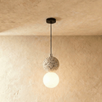 Clérachic two-globe pendant light with a cream terrazzo sphere above a glowing opal glass globe, hung on a black cord.