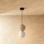 Clérachic two-globe pendant light with a cream terrazzo sphere above an unlit frosted glass globe on a black cord.