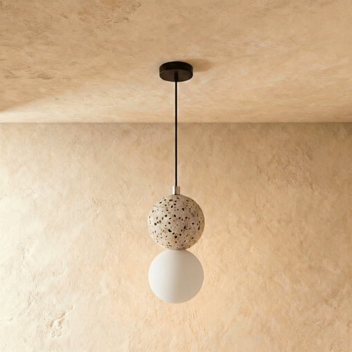 Clérachic two-globe pendant light with a cream terrazzo sphere above an unlit frosted glass globe on a black cord.