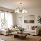 A Clérachic chandelier hangs low in a living room with a white sectional, sheer curtains and a rustic wood coffee table.
