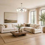This Clérachic chandelier hangs in a neutral sitting room with a white corner sofa, jute rug and a large landscape painting.