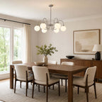Seen from the side, a Clérachic chandelier hangs low above a walnut dining table with cream chairs and a sideboard.