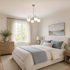 This Clérachic chandelier hangs in a bedroom with blue and cream bedding, pale wood bedside chests and a seascape painting.