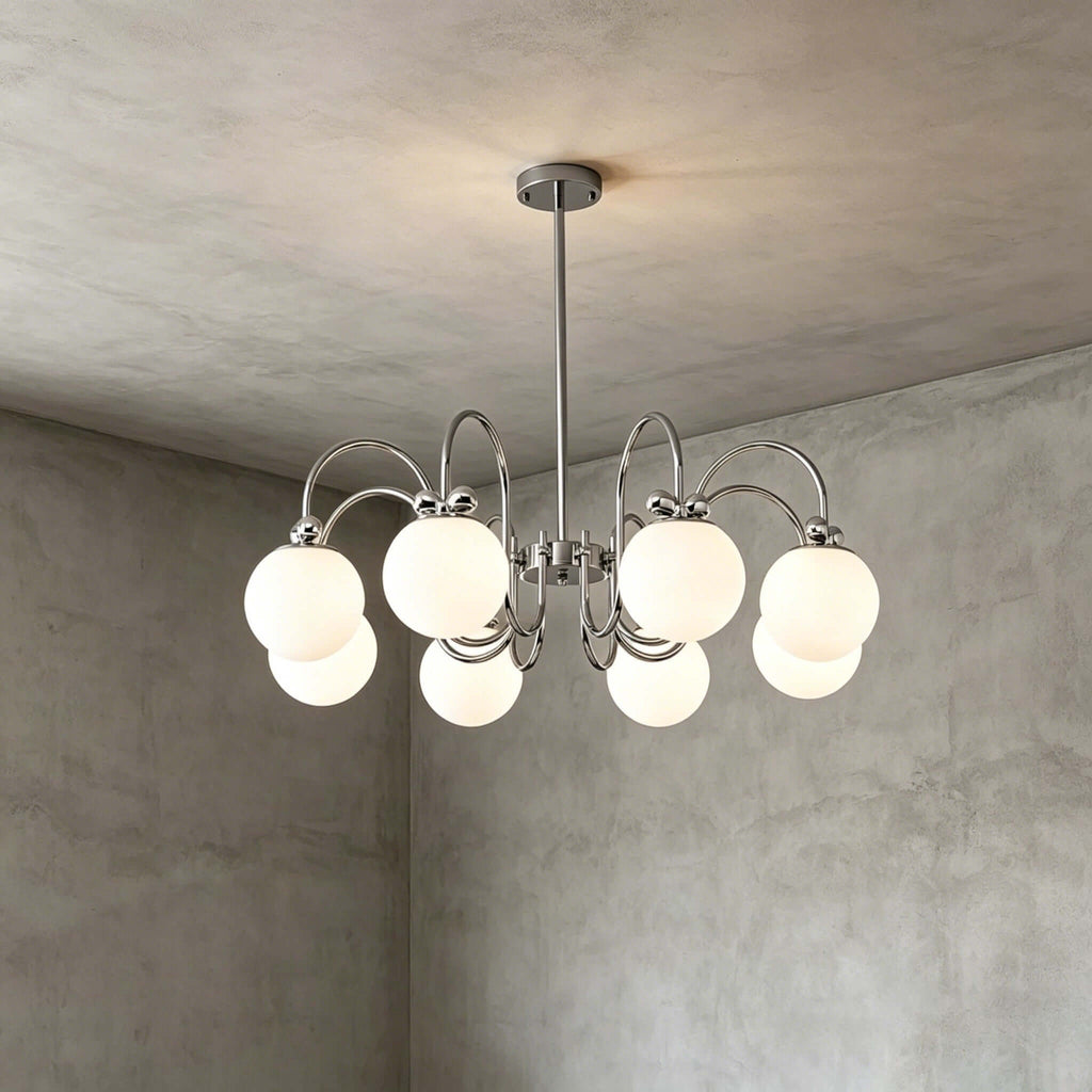 Closer view of the eight-globe version of this Clérachic chandelier, its chrome arms and white globes against a grey plaster corner.