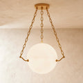 Clérachic glowing alabaster globe pendant held by three brass chains from a round brass ceiling canopy