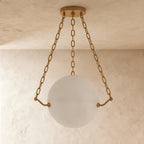 Clérachic unlit alabaster globe pendant, pale and softly veined, hung by three brass chains from a brass canopy