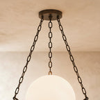 Close view of the Clérachic bronze canopy and three dark chains above the glowing alabaster globe