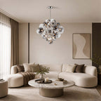 A Clérachic cluster chandelier of smoked and ribbed glass globes hangs above a round marble coffee table and a curved cream sofa.