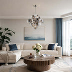 Clérachic glass-globe chandelier over a wooden drum coffee table, in a living room with blue curtains and a cream sofa.
