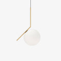 A Clérachic globe pendant on a plain white backdrop, its brass stem bent at an angle above a frosted white glass ball.