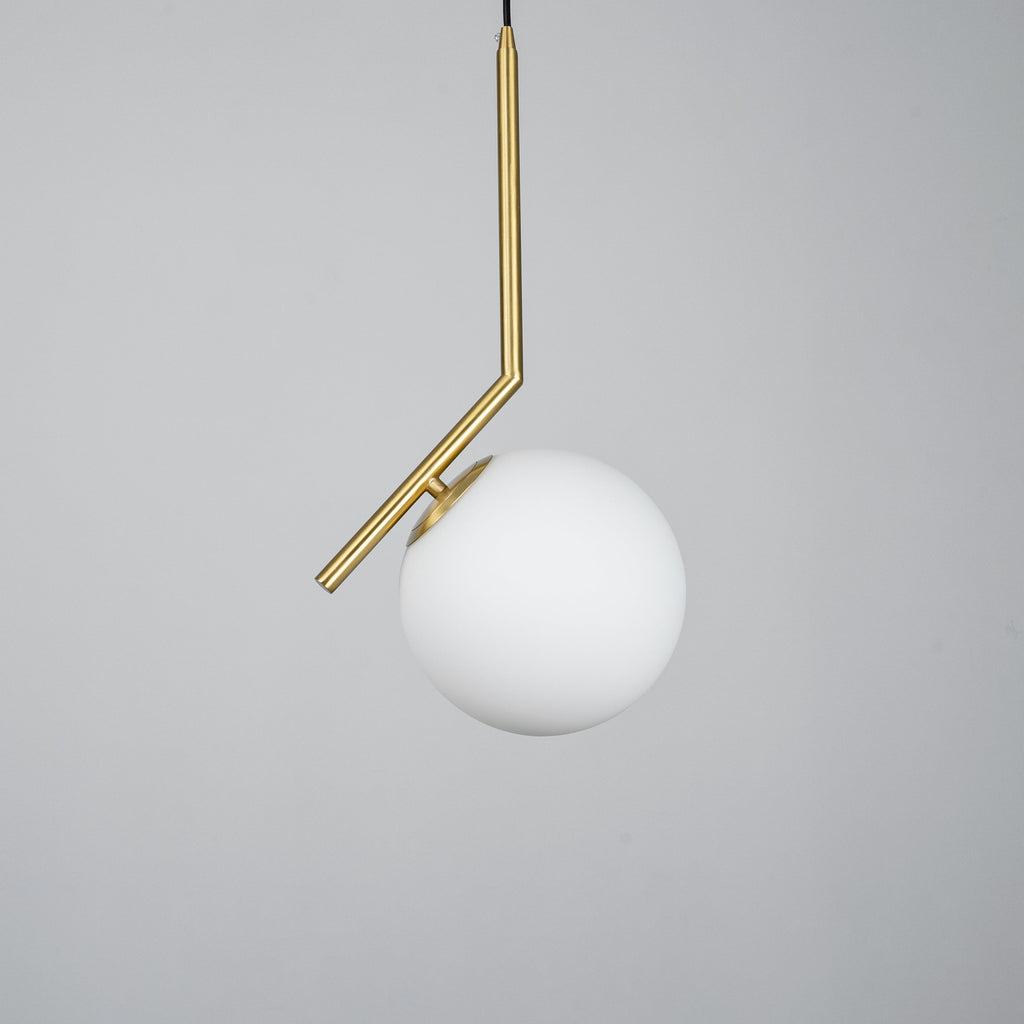 A Clérachic pendant with a smooth, unlit white glass globe and an angled brass stem, shot on a mid-grey backdrop.