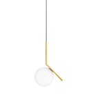 A Clérachic pendant with a brass stem and a small frosted globe hangs from a black cord on a plain white backdrop.