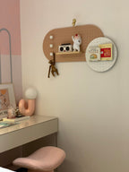 Small pink Clérachic lamp on a white desk in a pastel bedroom corner, with a peg board hanging above.