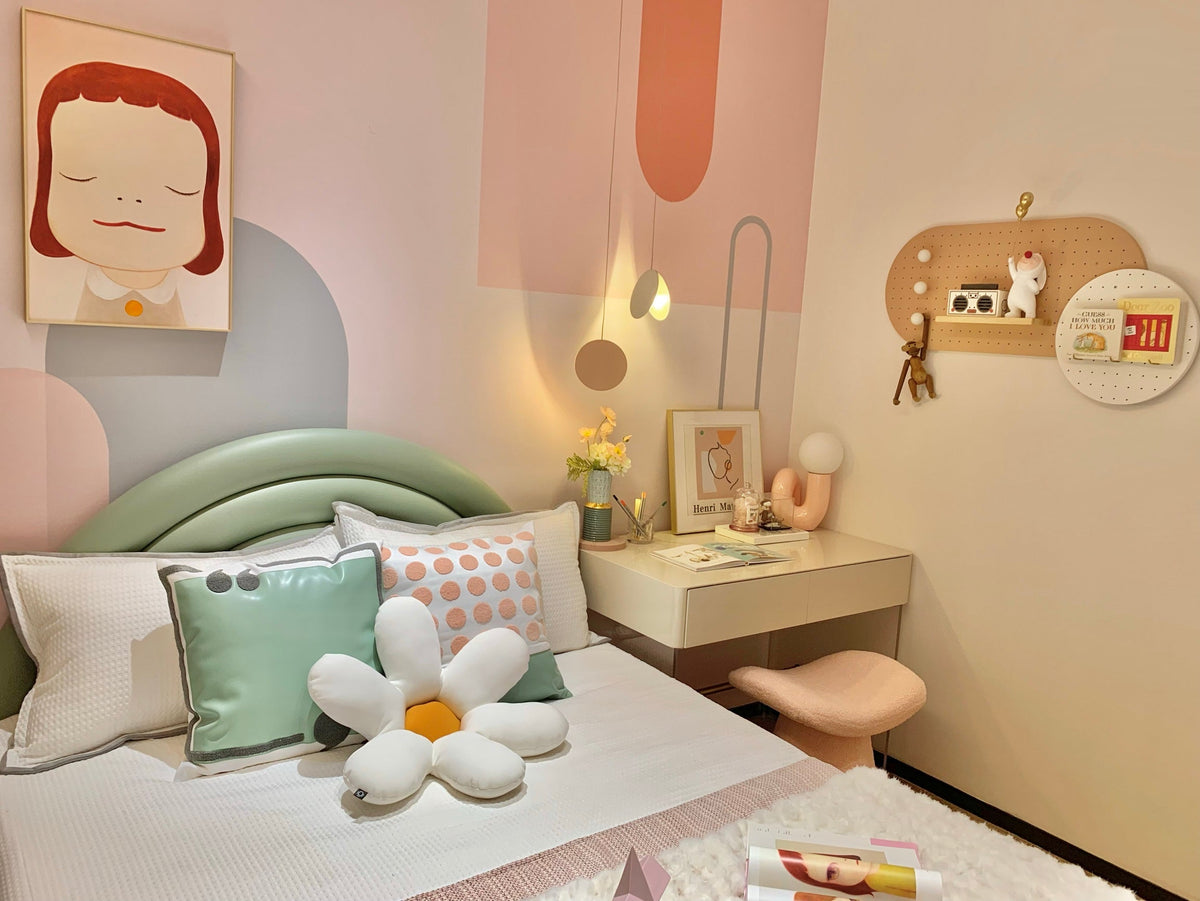 Pastel bedroom with a green bed and daisy cushion, a small Clérachic lamp on the desk in the far corner.