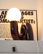 Lit dark red Clérachic table lamp, its globe bright and a warm glow showing in the base opening.