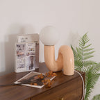 Peach Clérachic table lamp on a walnut chest, with a fern, a book and dried leaves around it.