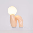Lit peach Clérachic table lamp on a clear block, a warm glow spreading from the globe over the base.
