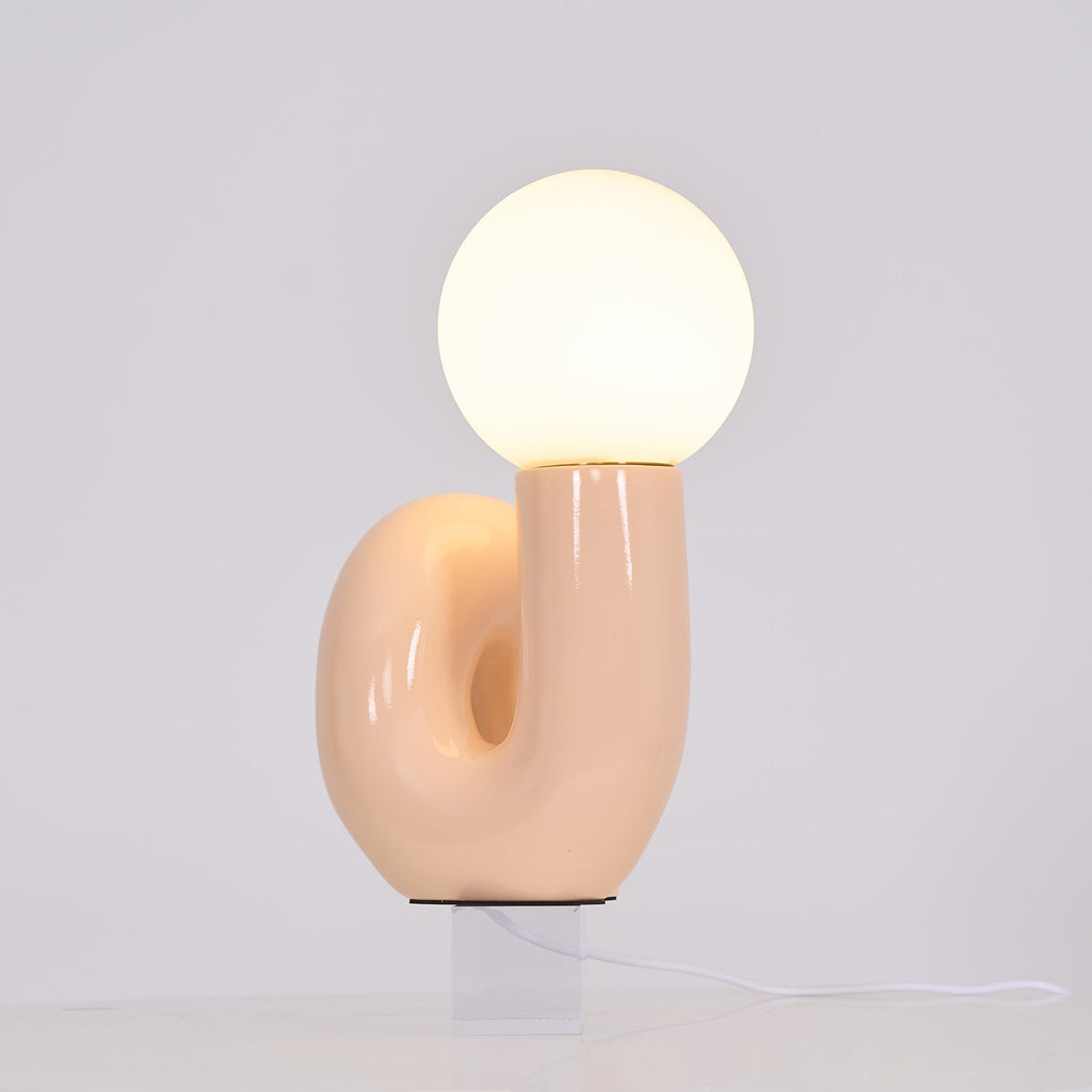 Lit peach Clérachic table lamp with the base opening in view, a soft glow filling the globe.