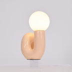 Lit peach Clérachic table lamp with the base opening in view, a soft glow filling the globe.