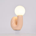 Peach Clérachic table lamp lit on a pale backdrop, warm light showing through the curve of the base.