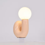 Peach Clérachic table lamp lit on a pale backdrop, warm light showing through the curve of the base.