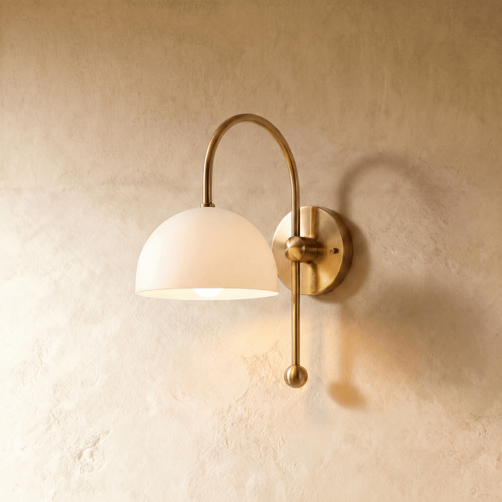 Clérachic wall lamp in brass with a white dome shade on an arched arm ending in a ball finial.