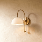 Clérachic wall lamp in brass with a white dome shade on an arched arm ending in a ball finial.
