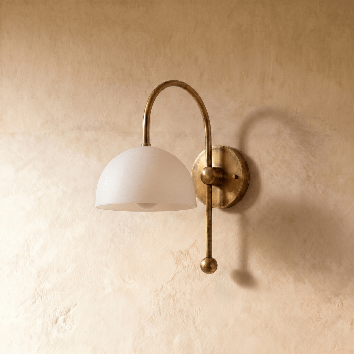 This vintage brass Clérachic wall lamp is shown from a different angle, the dome shade lit warmly.