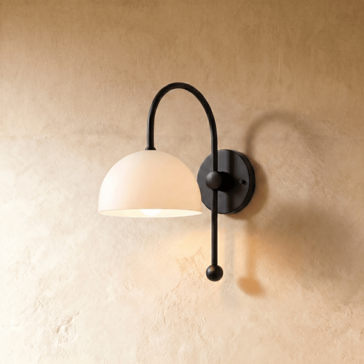 Clérachic wall lamp in matte black, its white dome shade set on an arched arm with a ball finial.