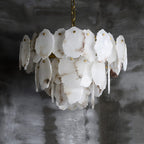 Angled view of the Clérachic Gloire chandelier where the alabaster veining runs grey and rose across the overlapping plates.