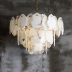 Warm light escaping between the tiers of the Clérachic Gloire alabaster chandelier, turning the thinner plates amber.