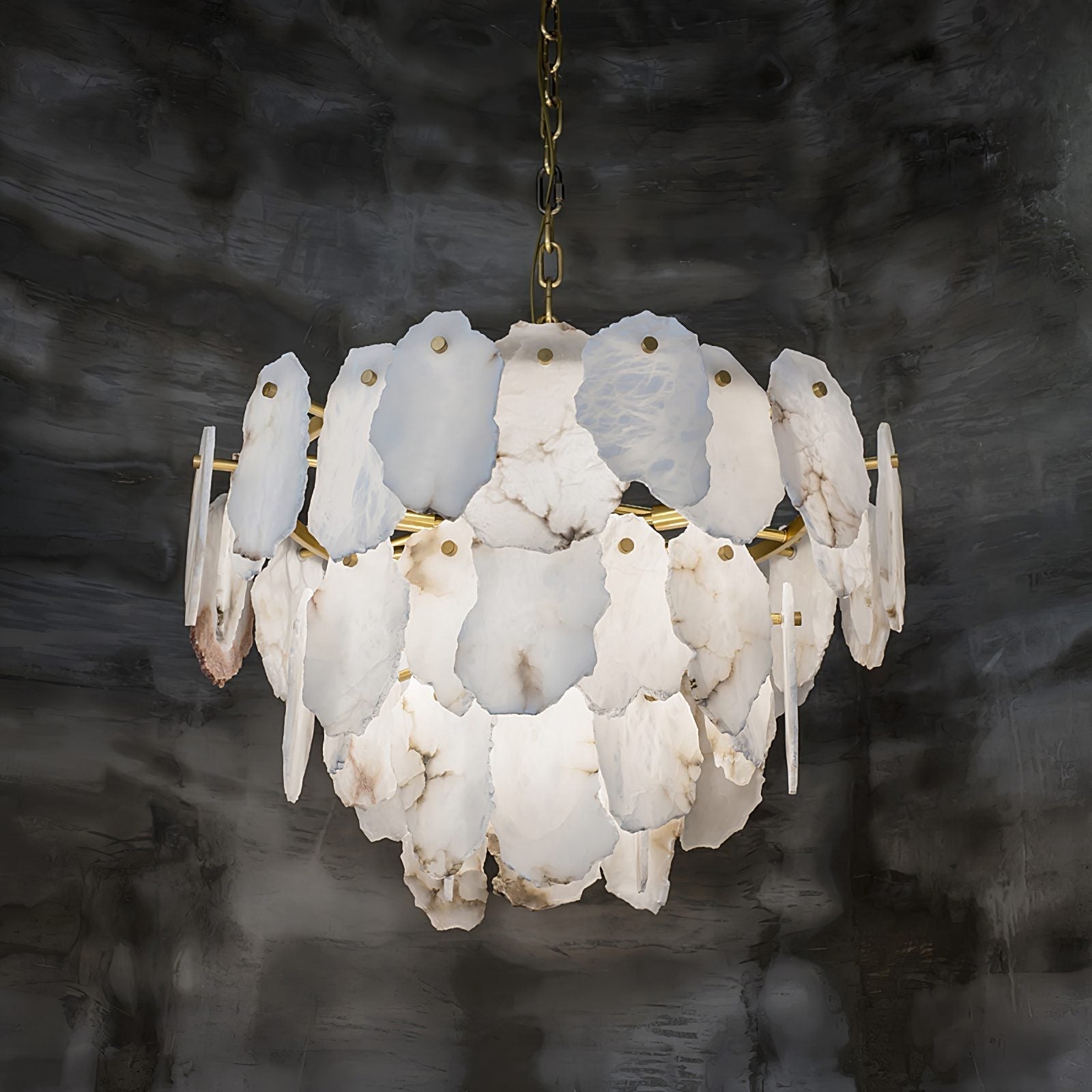 The Clérachic Gloire chandelier lit softly in a dim room, the alabaster reading cool and milky against dark plaster.