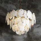 Close view of the lit Clérachic Gloire chandelier, brass arms visible behind three staggered rings of alabaster.