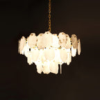 Clérachic Gloire alabaster chandelier fully lit against black, each stone plate glowing from within on its brass chain.
