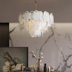 Clérachic Gloire alabaster chandelier lighting a console below a veined marble wall, warm glow spilling from the lower tier.