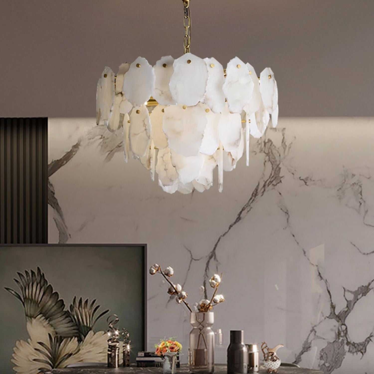 Clérachic Gloire alabaster chandelier lighting a console below a veined marble wall, warm glow spilling from the lower tier.