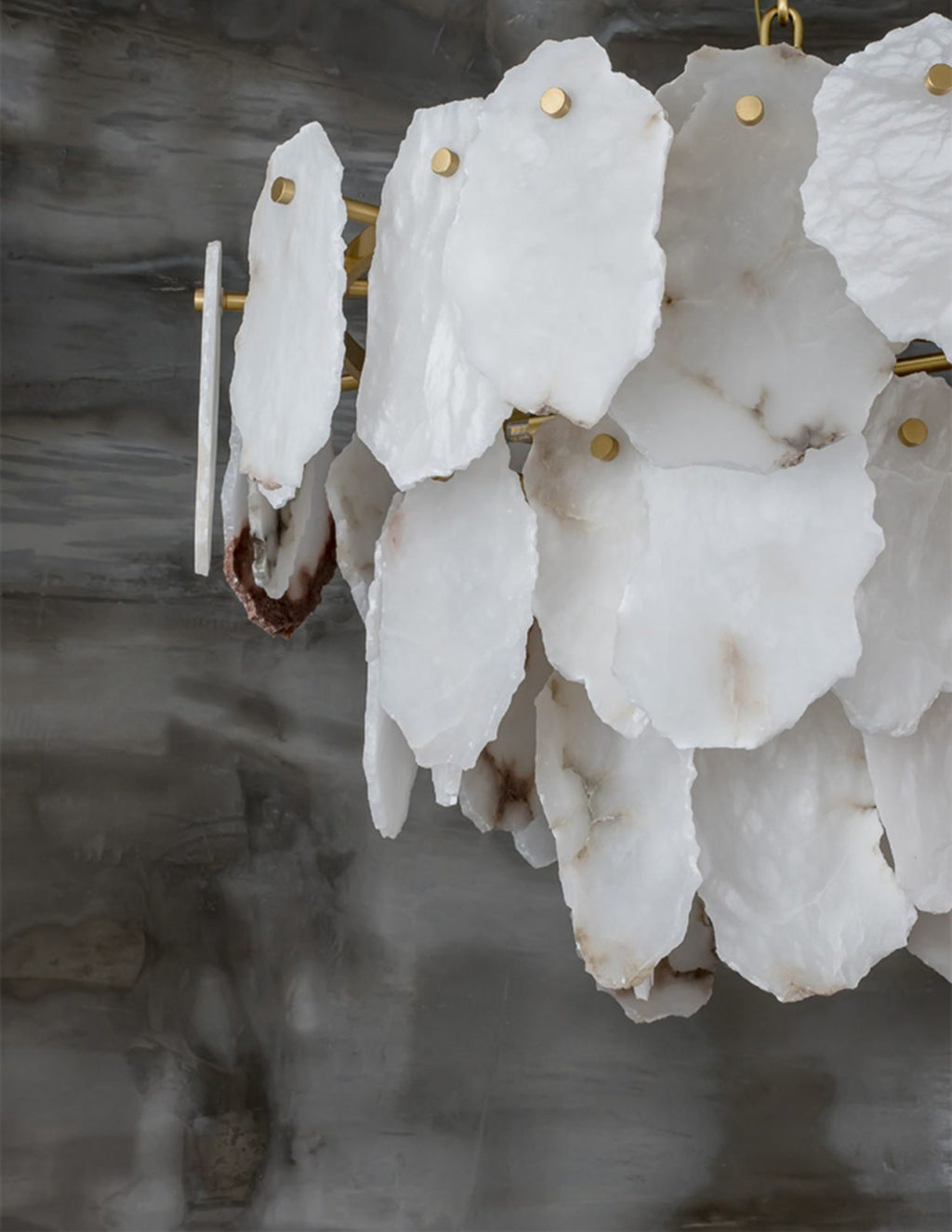 Detail of the Clérachic Gloire chandelier showing raw cut edges, brass pins and a rust-red seam running through one plate.