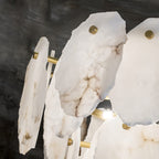 Close crop of the Clérachic Gloire chandelier where one lit lamp catches the thick, hand-cut alabaster plates from behind.