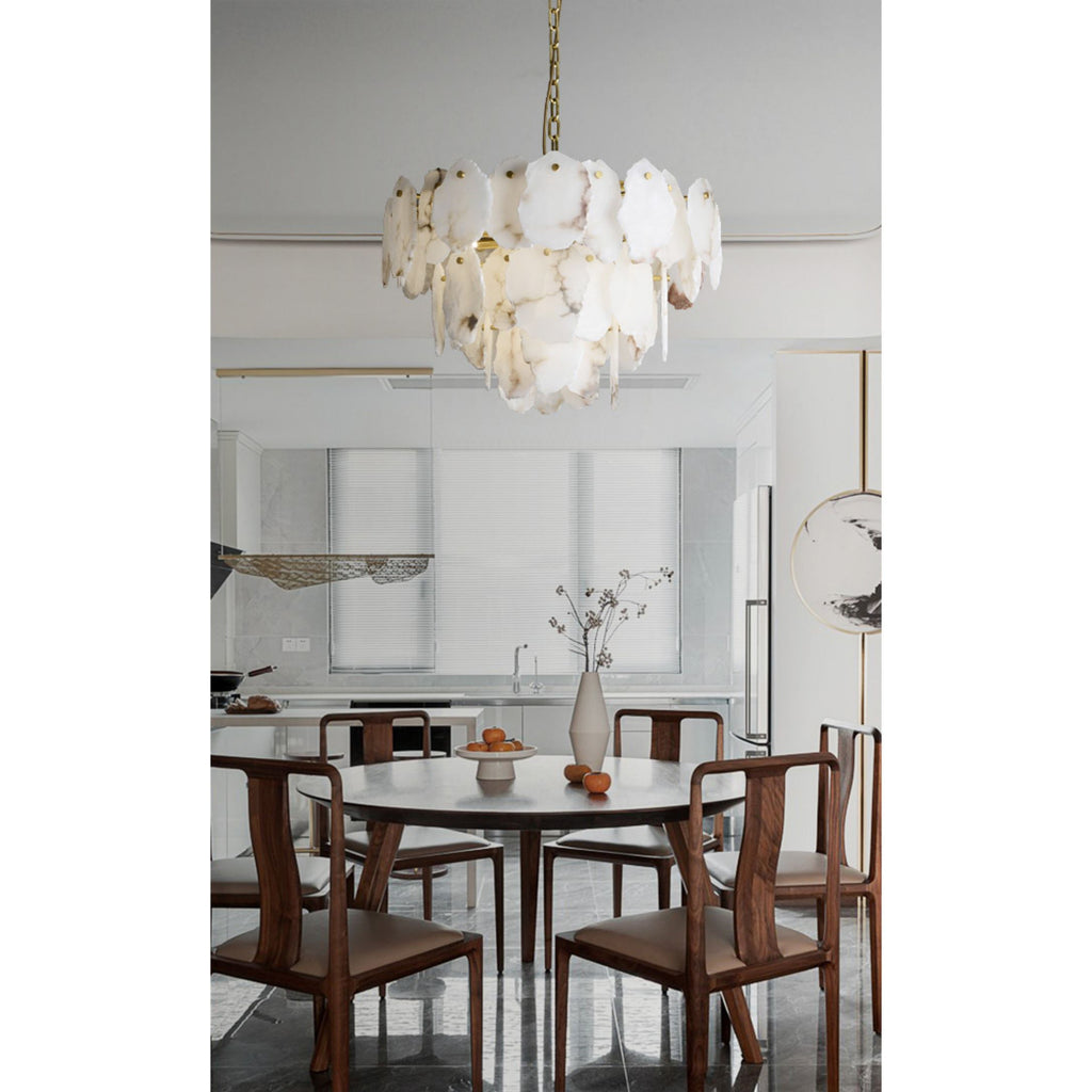 Clérachic Gloire alabaster chandelier centred above a round walnut dining table in a bright open-plan kitchen.