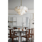 Clérachic Gloire alabaster chandelier centred above a round walnut dining table in a bright open-plan kitchen.