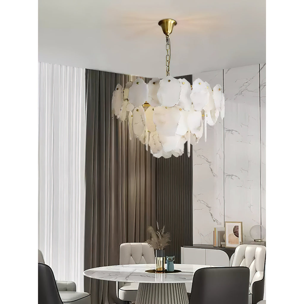 Clérachic Gloire alabaster chandelier over a marble dining table, warm light lifting the veining in the stone plates.