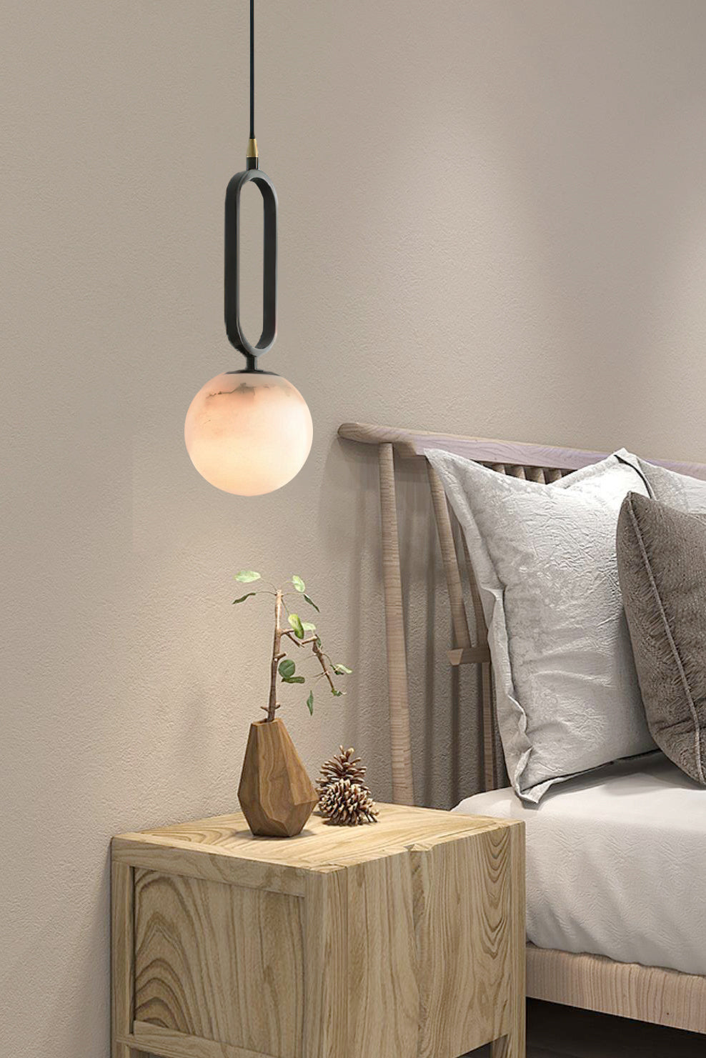 The Clérachic Gloruvyd pendant hangs low over an oak nightstand, its black frame crisp against a warm grey bedroom wall.
