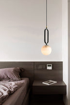 Clérachic Gloruvyd casts a soft globe of light above a dark walnut headboard and plum bed linen.