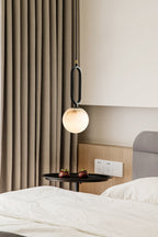 The Clérachic Gloruvyd pendant drops beside floor-length curtains, lighting a black round side table at the bedside.