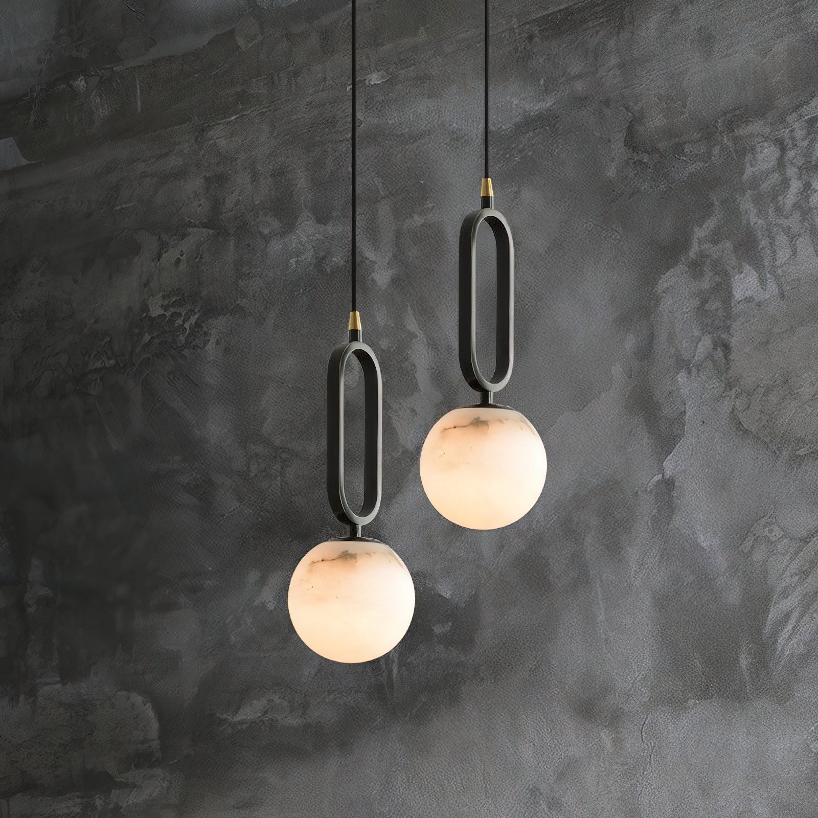 The Clérachic Gloruvyd pendants hang as a pair on raw grey microcement, alabaster reading warm against cool concrete.