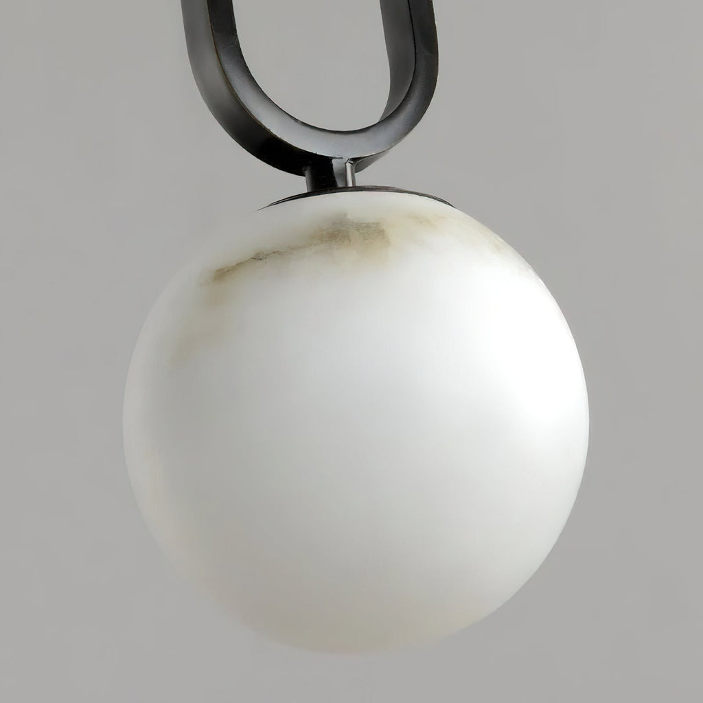Clérachic Gloruvyd in close-up, the black frame's arc meeting a hand-carved alabaster globe streaked with grey veining.